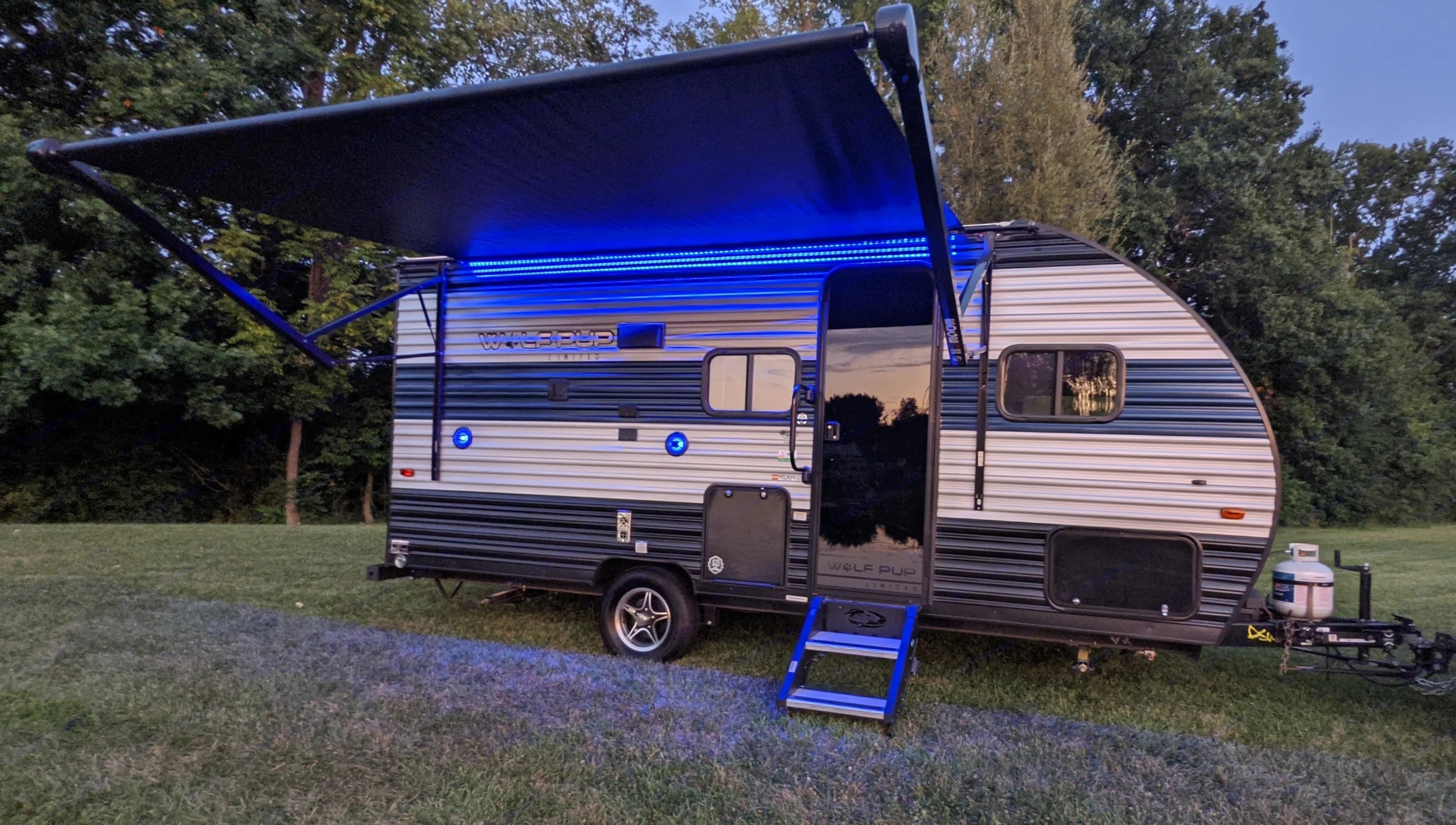 Bright blue LED awning lights illuminate this RV rental travel trailer. Perfect for camping adventures, with steps ready.. Forest River Cherokee Wolf Pup 2021