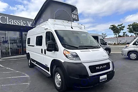 White Ram ProMaster camper van with pop-top roof for RV rental, parked at Classic Vans. Other vans nearby.. Winnebago Solis 2023