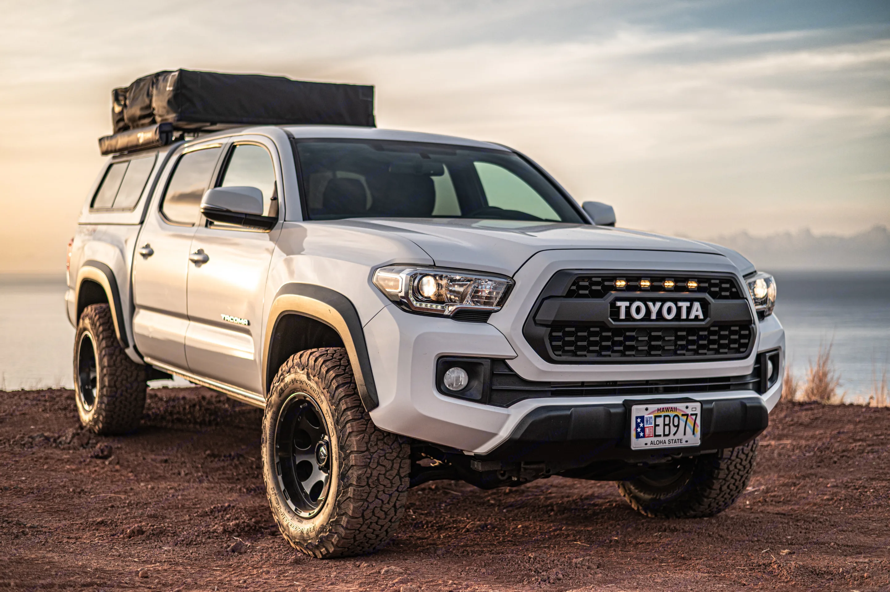 A white Toyota Tacoma truck with a rooftop tent, ideal for your next outdoor adventure or **RV rental** road trip by the sea.. Custom Camper 2016