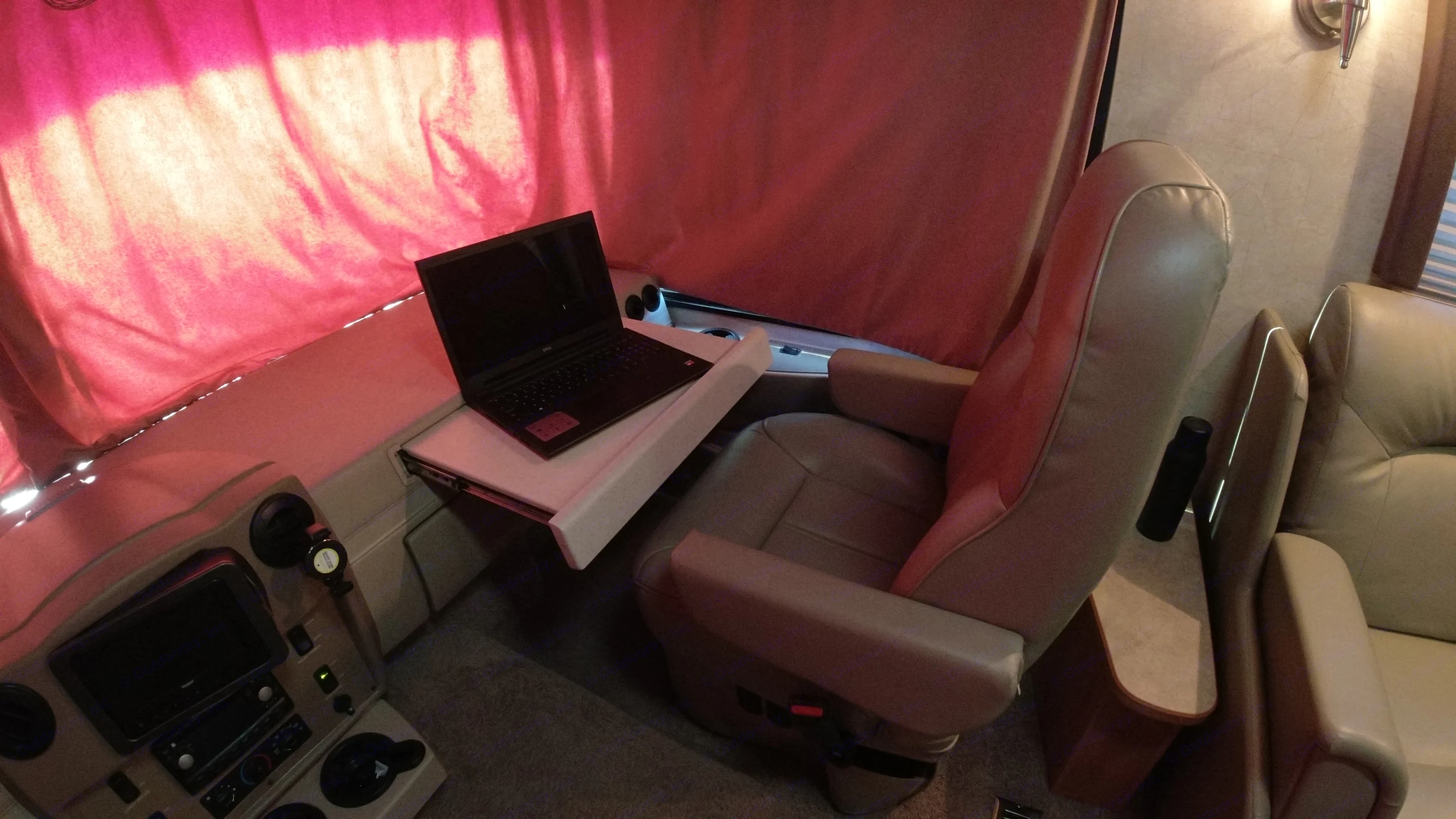 RV rental offers a mobile workspace: laptop on a pull-out table near comfortable seats and bright curtains.. Winnebago Voyage 2008