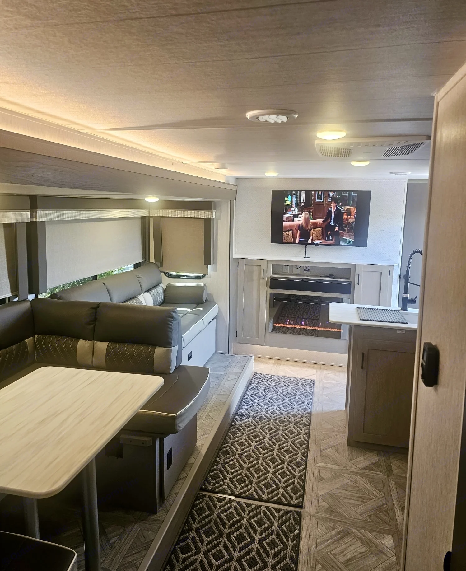 This modern RV rental features a comfortable living space with an L-shaped sofa, dining table, TV, and electric fireplace.. SALEM CRUISE LITE PLATINUM 28VBLX 2024