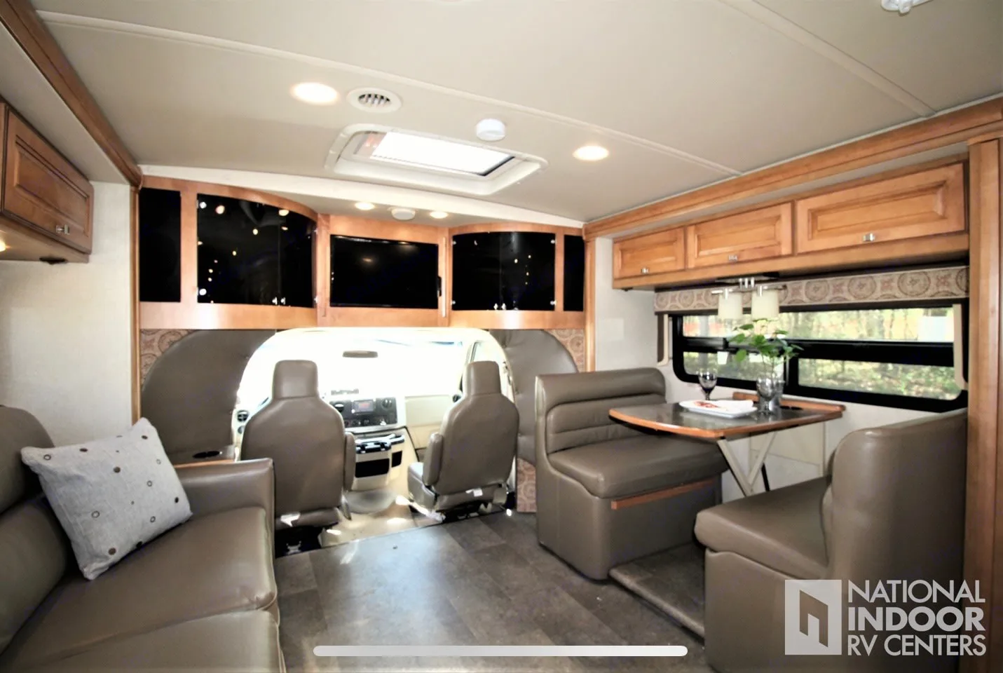 Spacious RV rental interior: living area, dining booth, and forward cockpit with mounted screens.. Itasca Cambria 2014