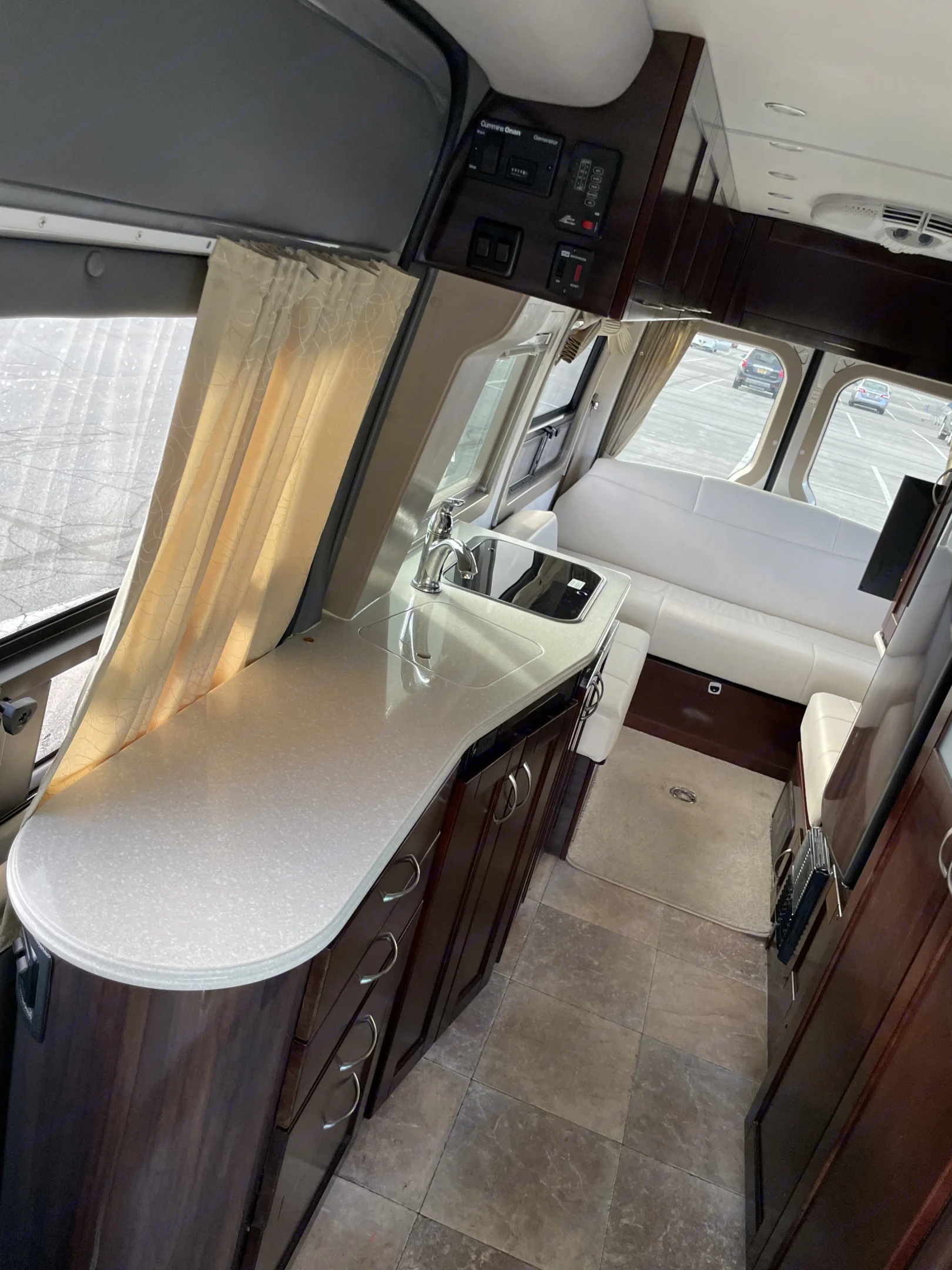 Inside a premium RV rental: kitchenette with sink, elegant wood cabinets, and rear sofa seating. Ideal for travel.. Pleasure-Way Pleasure-Way Class B 2013