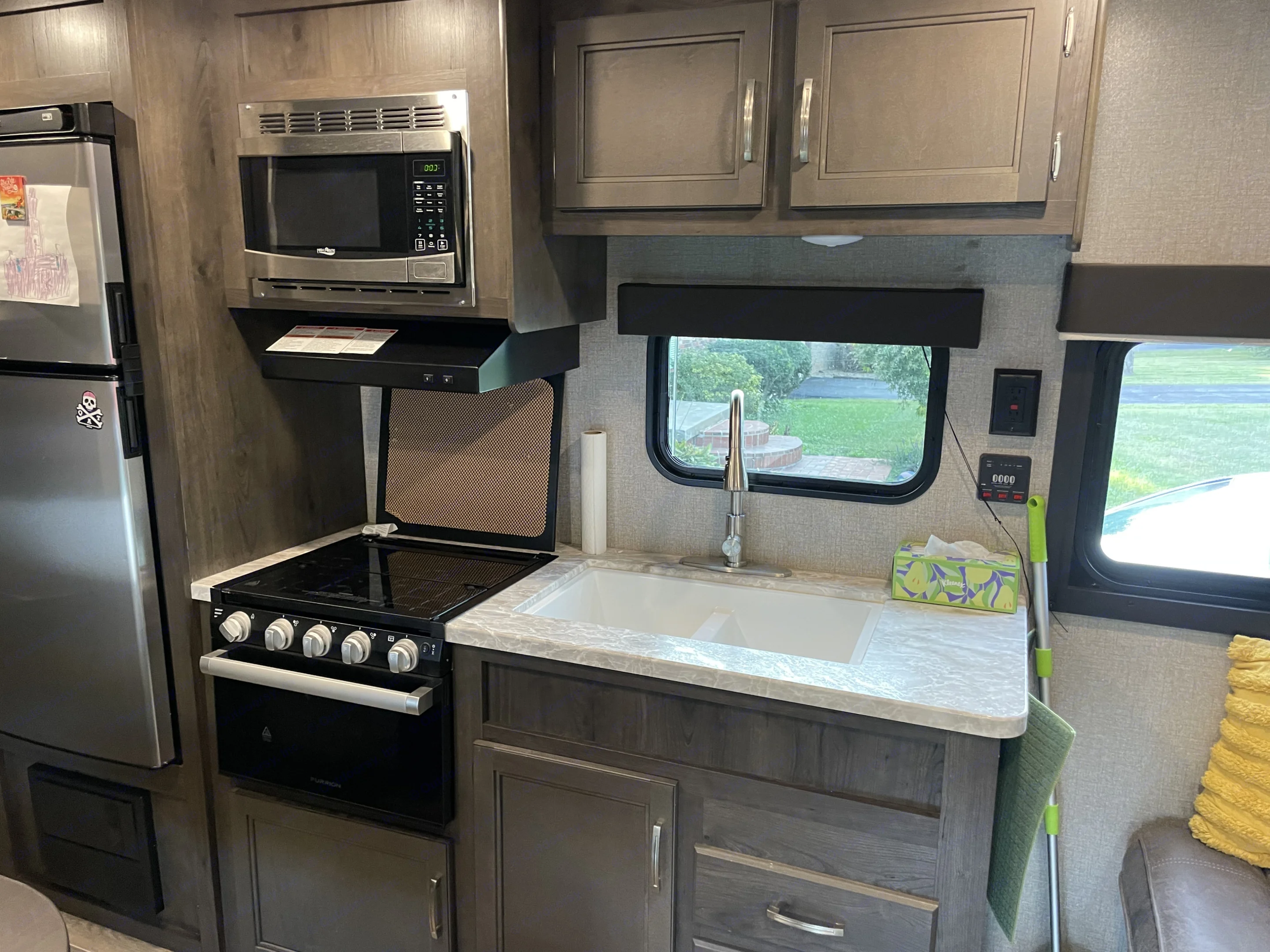 Functional RV rental kitchen with modern appliances: fridge, microwave, stove, and a sink by the window.. Jayco Jay Flight SLX 2021