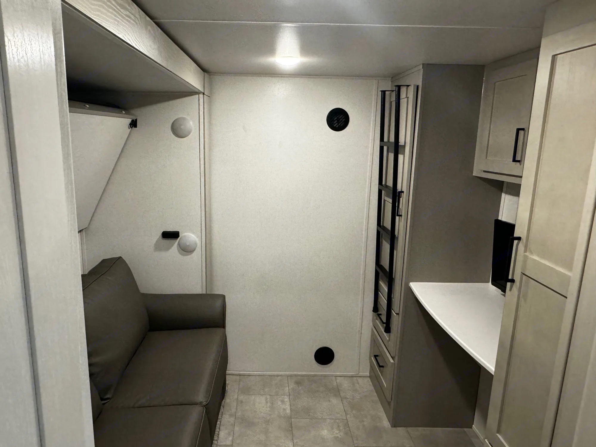 Explore this RV rental interior: a cozy gray sofa, bunk bed, desk, and storage create a functional living space.. Forest River Columbus 379 MBC 2022