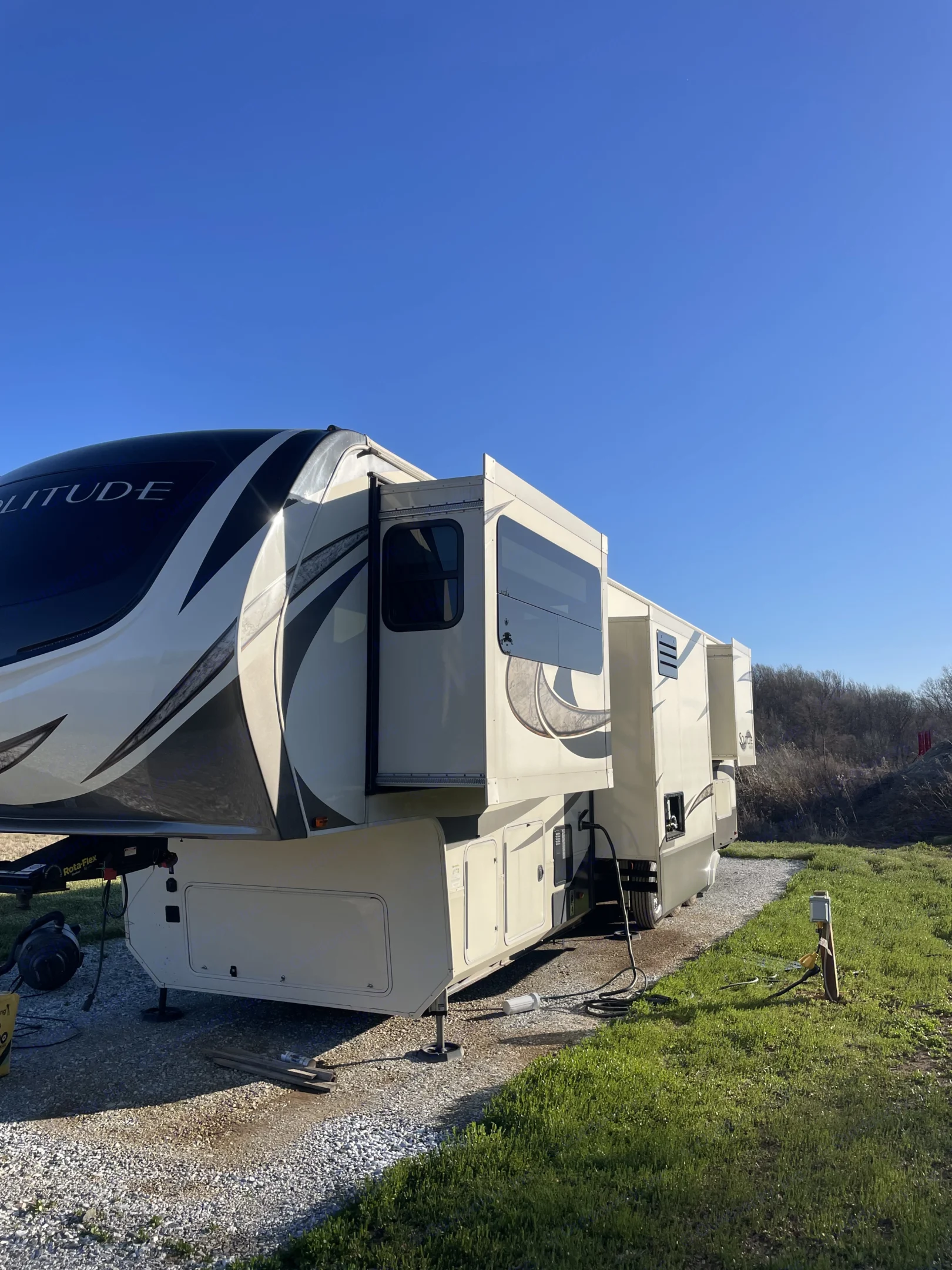 Spacious Grand Design Solitude fifth-wheel RV rental parked at a sunny campsite with extended slide-outs, ready for adventure.. Grand Design Solitude Toy Hauler 2018