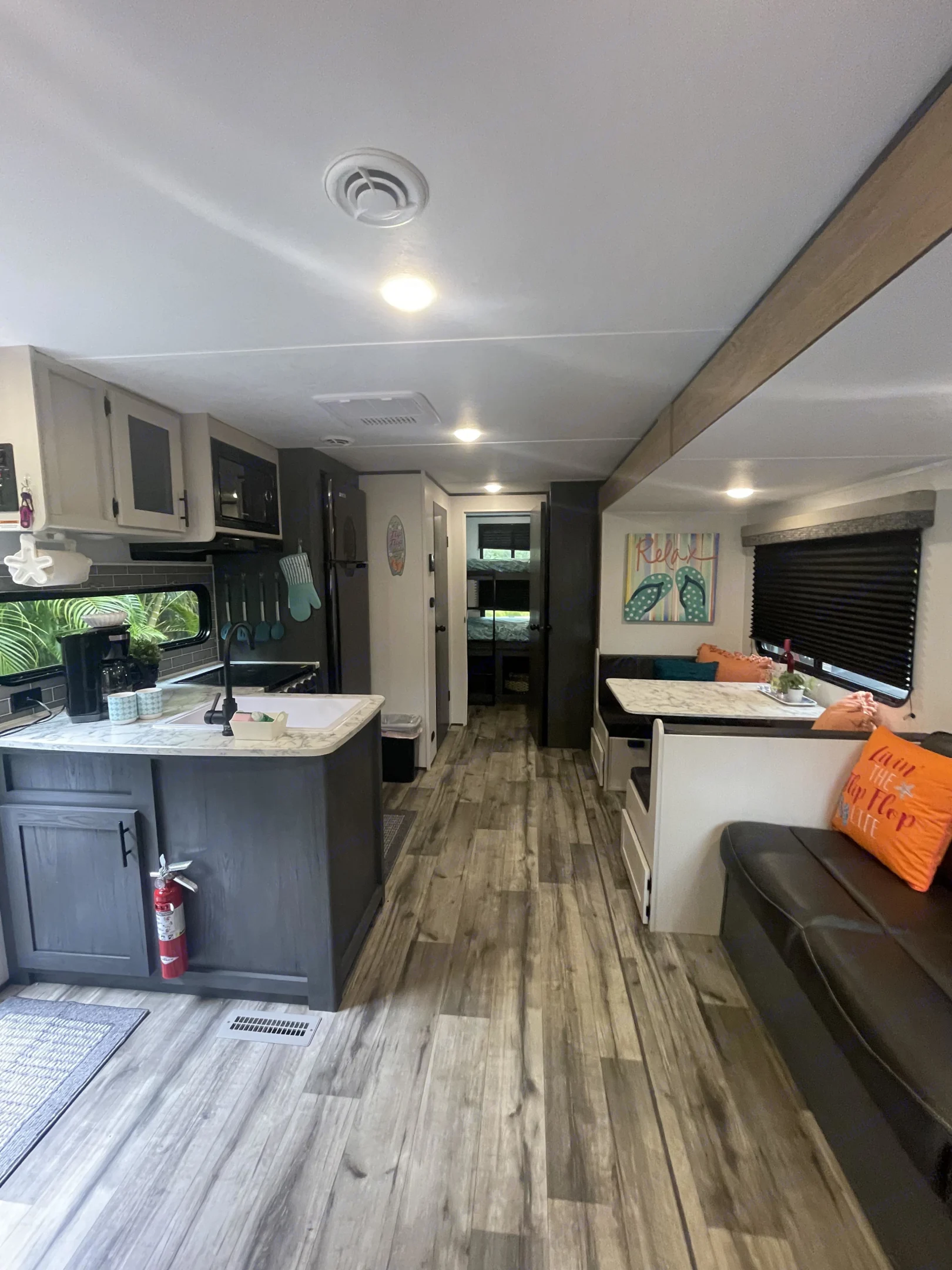 Spacious, modern RV rental interior with a well-equipped kitchen, dining area, and sofa, leading to. Dutchmen Aspen Trail 2024