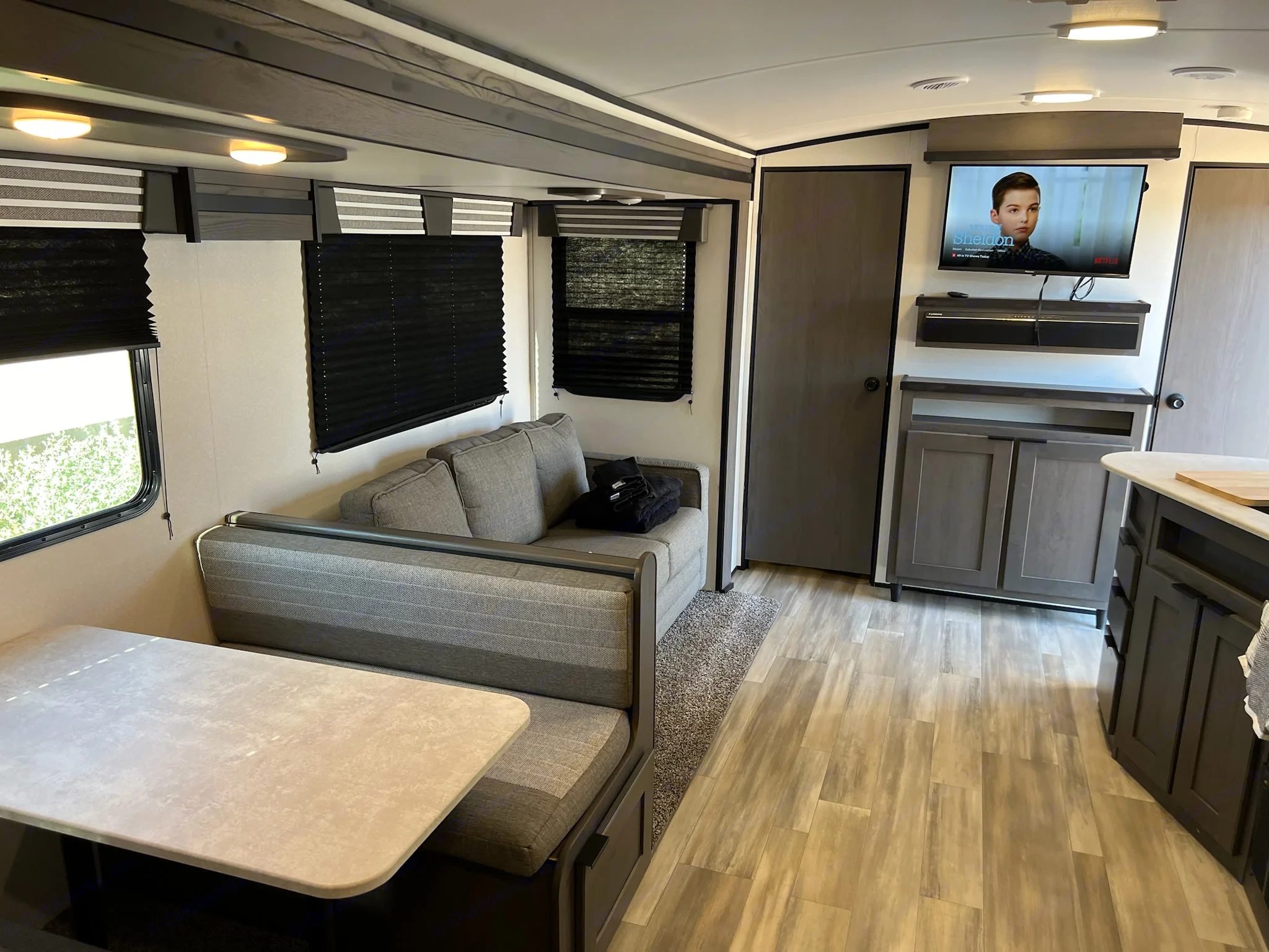 Explore this modern RV rental's cozy living area, featuring a dinette, sofa, and TV with entertainment storage.. Cruiser RV MPG Ultra Lite 2021