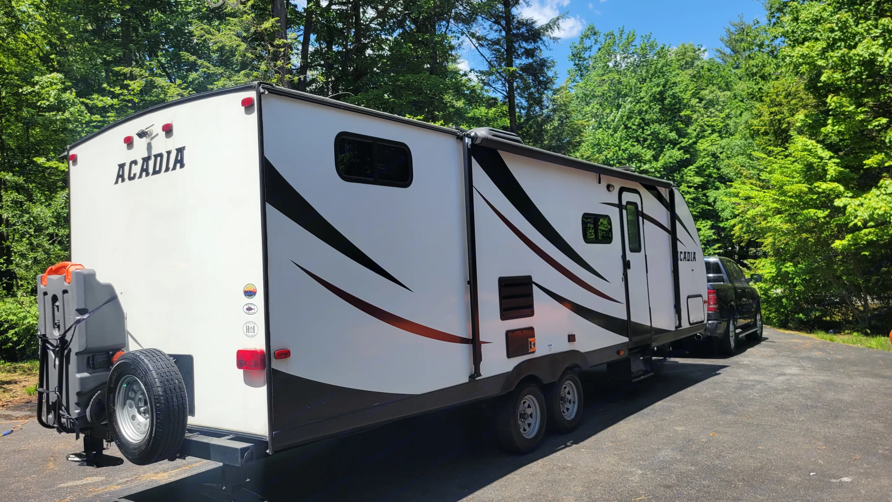 White "Acadia" RV rental, a travel trailer, is parked on asphalt with trees & blue sky, ready for adventure.. Forest River Acadia 2018