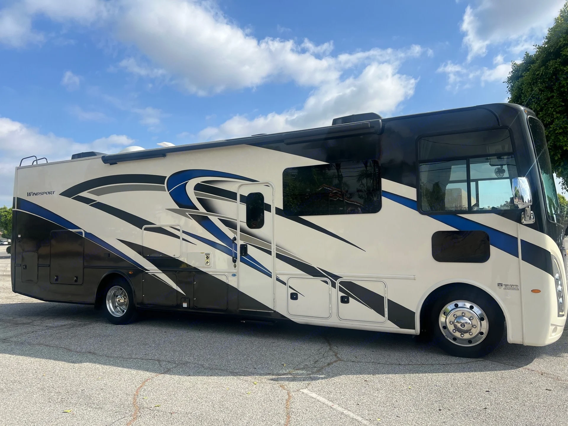 Side view of a white, black, and blue Thor Windsport Class A motorhome for rv rental.. Thor Windsport 2022