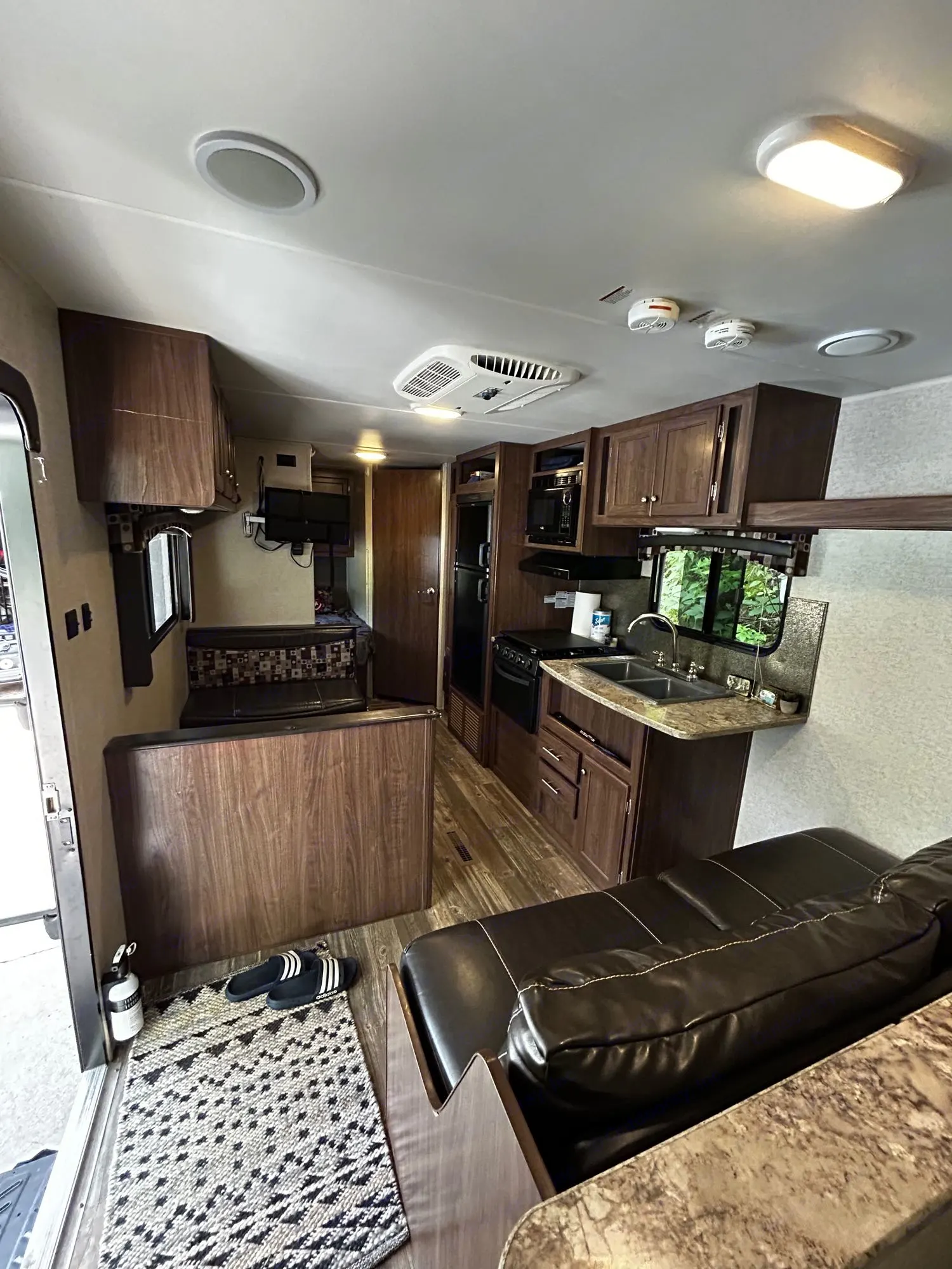 This RV rental showcases a functional kitchen, dining booth, and living area with sofa, offering a cozy mobile living space.. Heartland RVs Pioneer 2016