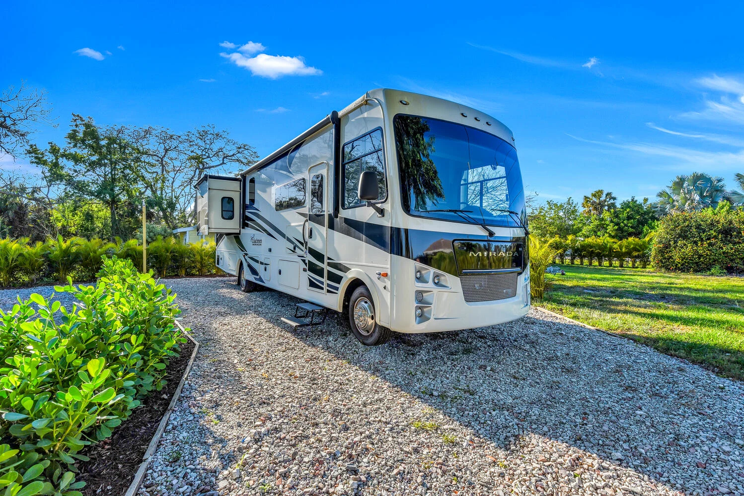 Spacious Mirada RV rental parked on a sunny gravel lot with lush greenery, ready for your next outdoor adventure.. Coachman Mirada 2021