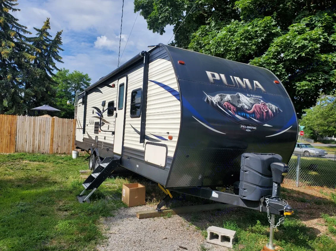 Puma travel trailer RV rental parked outdoors: A large, black and beige unit with extended steps.. Forest River Palomino Puma 2018