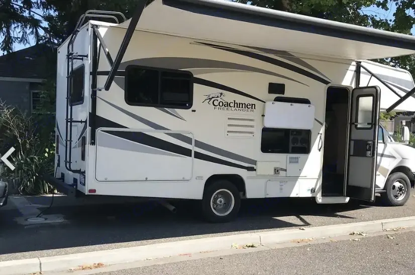 White Coachmen Freelander RV rental parked, with its awning extended and entry door open. This motorhome is ready for adventure.. Forest River Coachmen Freelander 2017