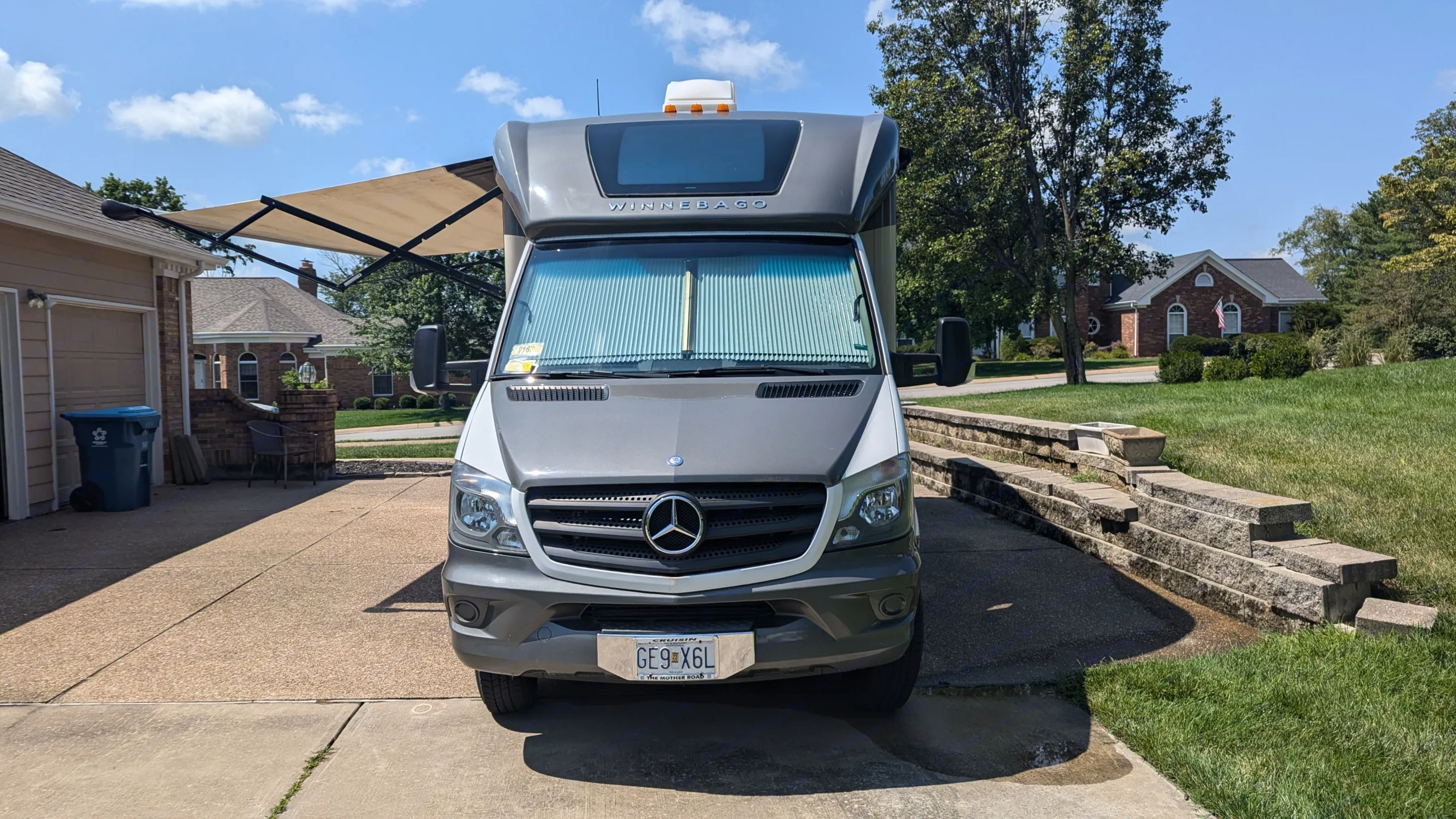 Winnebago Mercedes Sprinter RV rental parked on a sunny residential driveway with an extended awning.. Winnebago View 2015