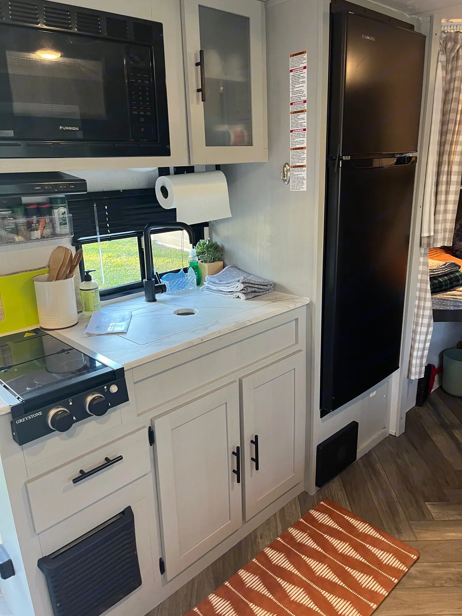 This RV rental kitchen has a black microwave, fridge,. Forest River Wildwood FSX 2021