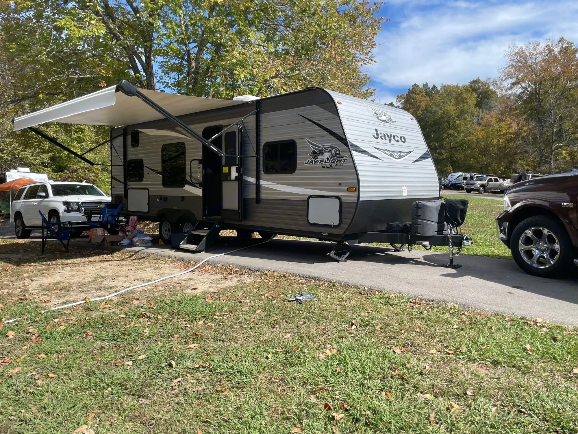 This spacious RV rental, a Jayco travel trailer, is set up with an awning at a peaceful, tree-filled campsite.. Jayco Jay Flight SLX 2021