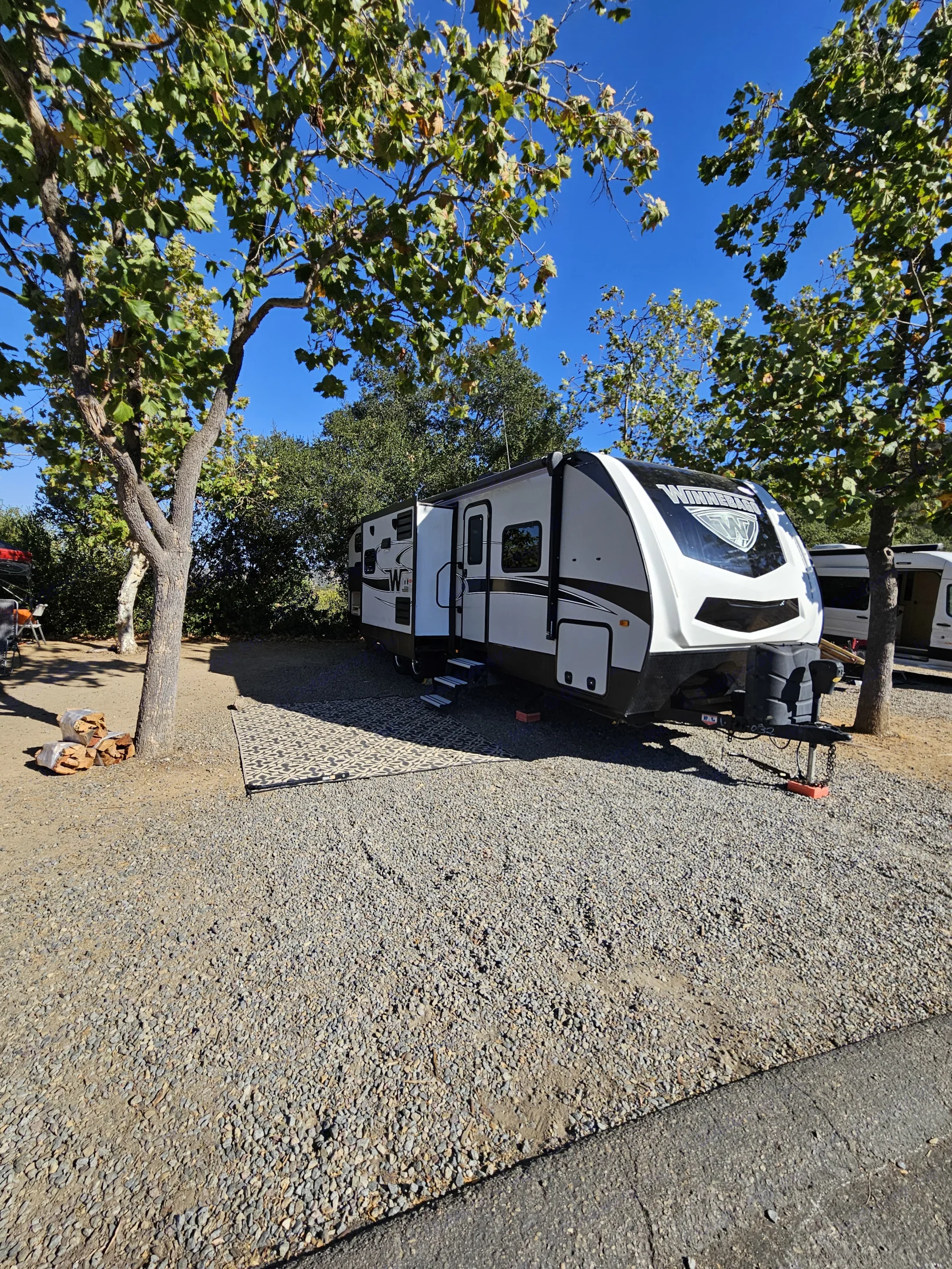 A white RV rental is perfectly set up at a sunny gravel. Minnie Minnie Plus 2019