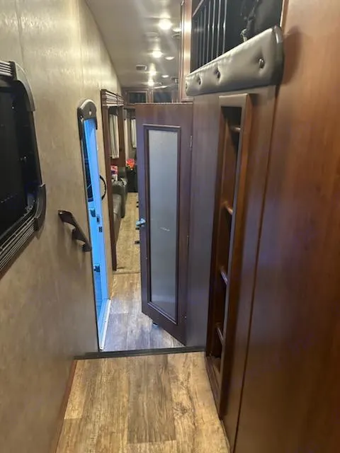 RV rental interior: A narrow hallway with wood floors, a bath door, and an overhead bunk with ladder.. Jayco Eagle 2017