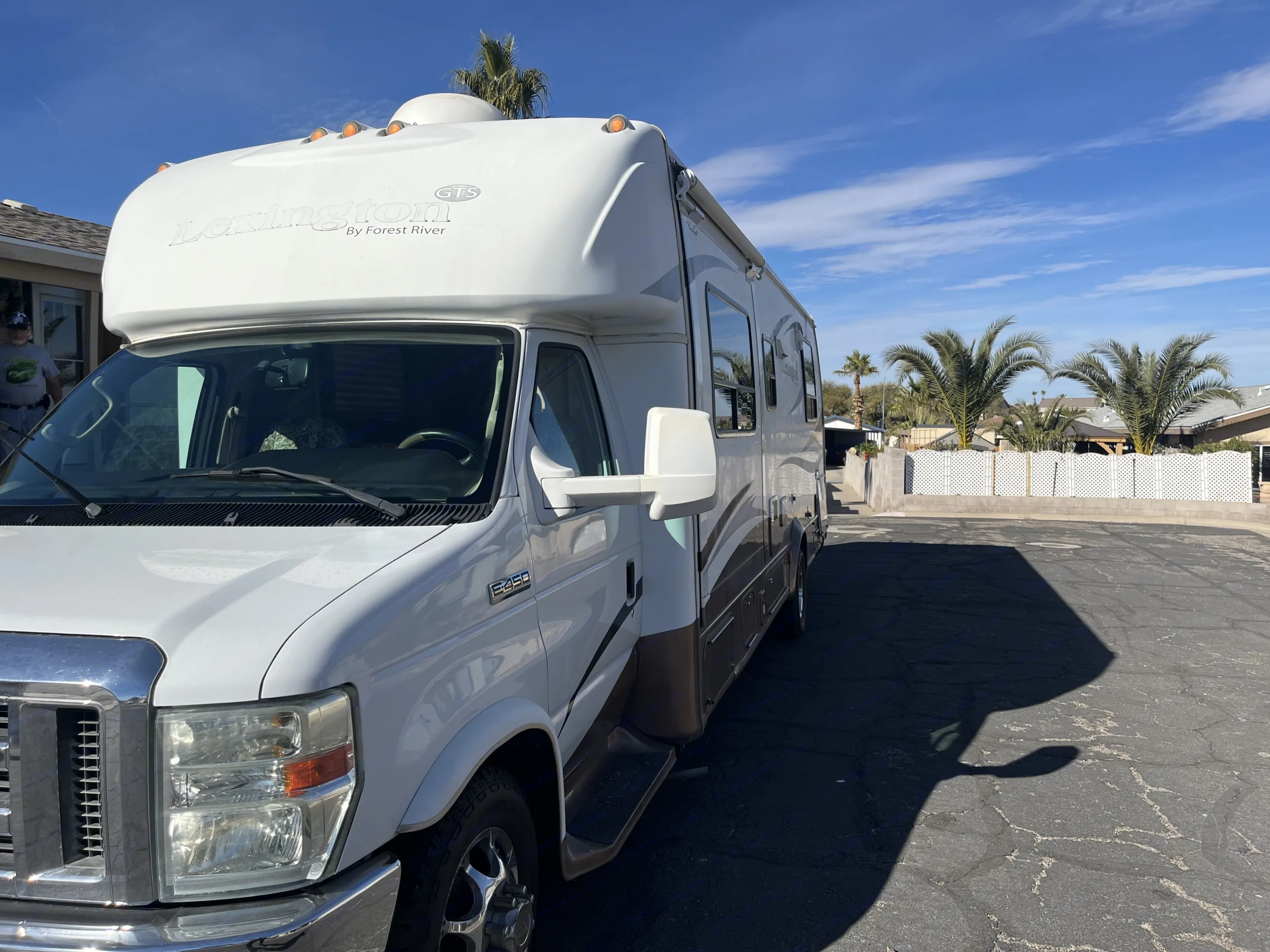 White Forest River Lexington Class C RV rental, a Ford E-450 motorhome, parked outdoors under a blue sky with palm trees.. Lexington Grand Touring 2010