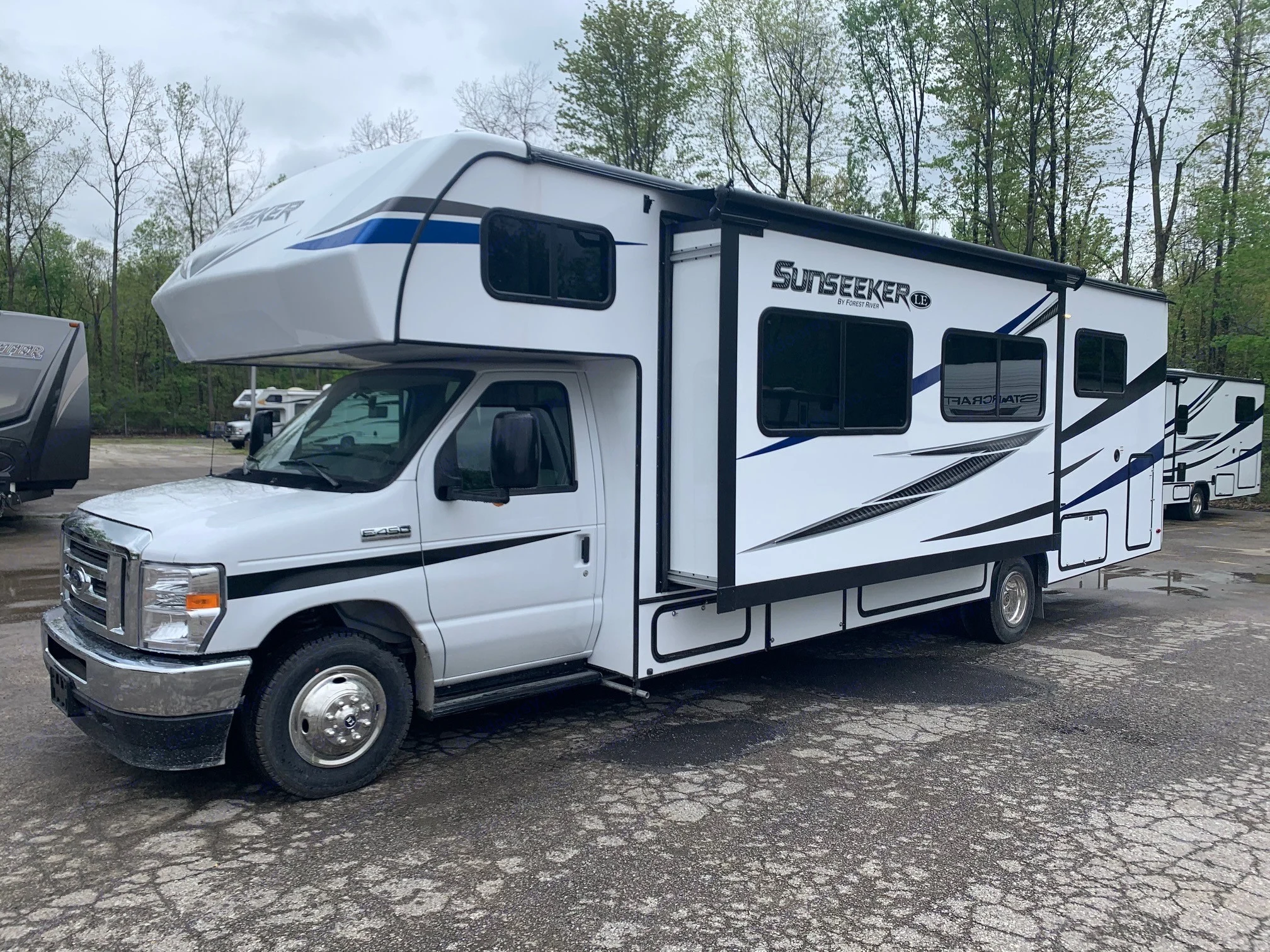 Explore with this white Sunseeker Class C RV rental, slide-out extended, parked on asphalt. Your road trip adventure awaits!. Forest River Sunseeker 2026