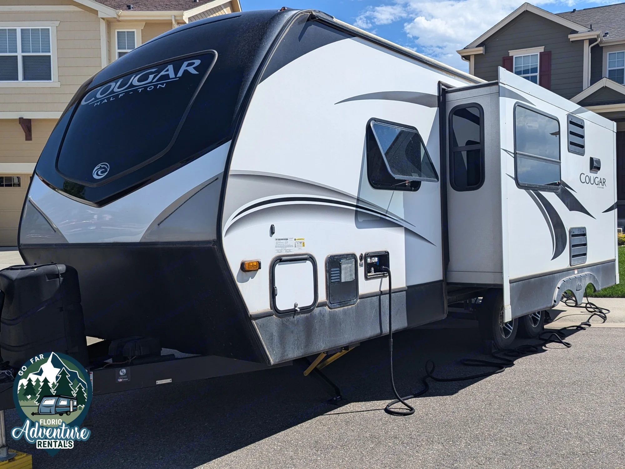 This Cougar travel trailer RV rental, white and black, is parked with its slide-out extended.. Keystone RV Cougar 2021