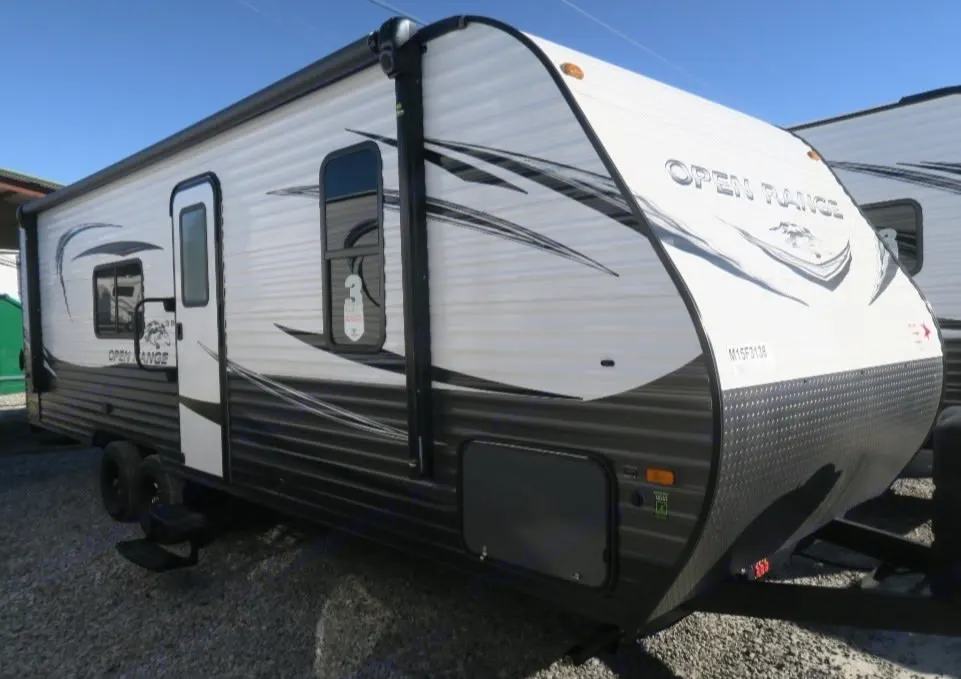 This white and grey Open Range travel trailer is perfect for your next RV rental adventure. Parked on a gravel lot.. Open Range Open Range 2021
