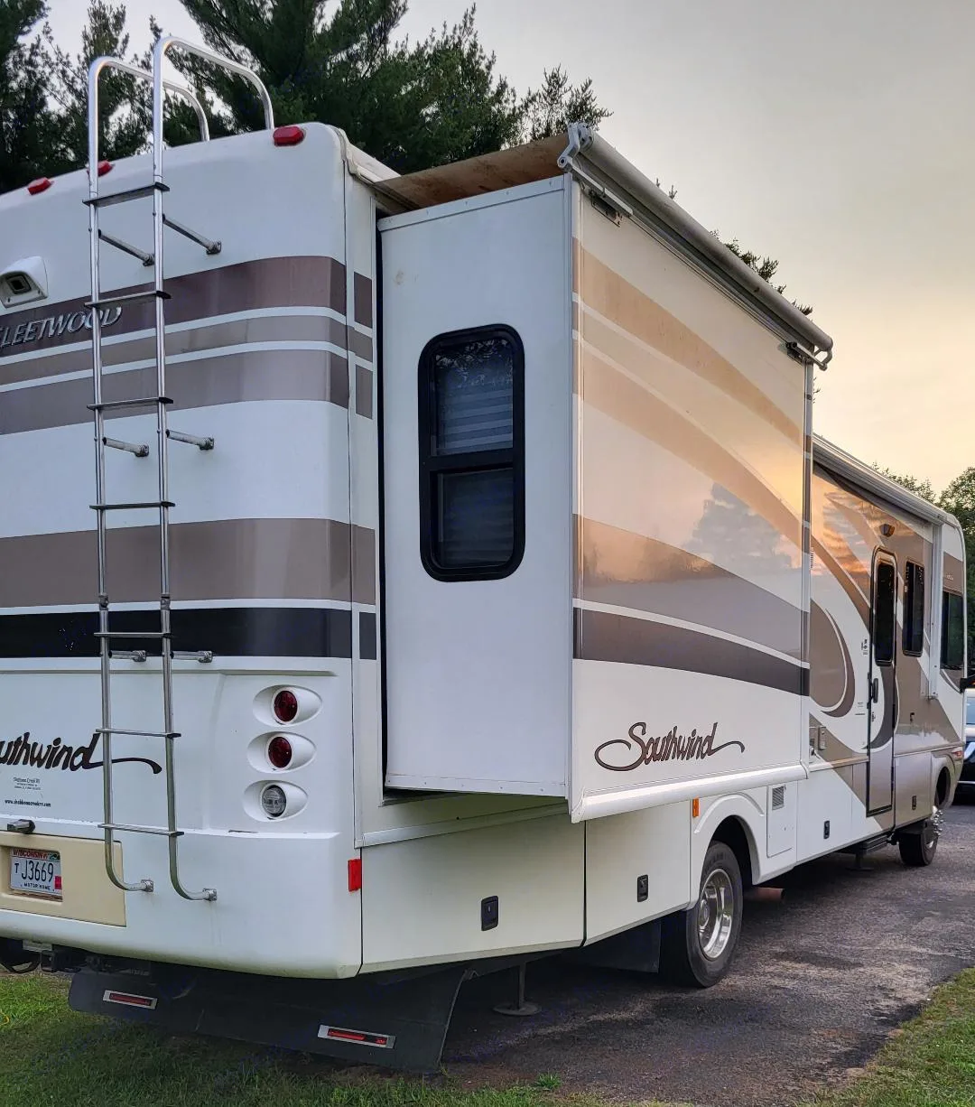 Rear-side view of a white & brown Fleetwood Southwind RV rental (motorhome) with its slide-out extended, parked.. Southwind Southwind Motorhome 2005
