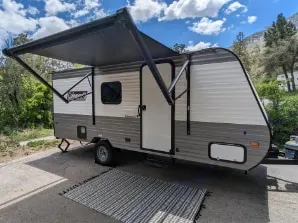 This gray and white travel trailer RV rental with extended awning is perfect for your next outdoor camping or road trip adventure.. Dutchmen Coleman Lantern LT 2023