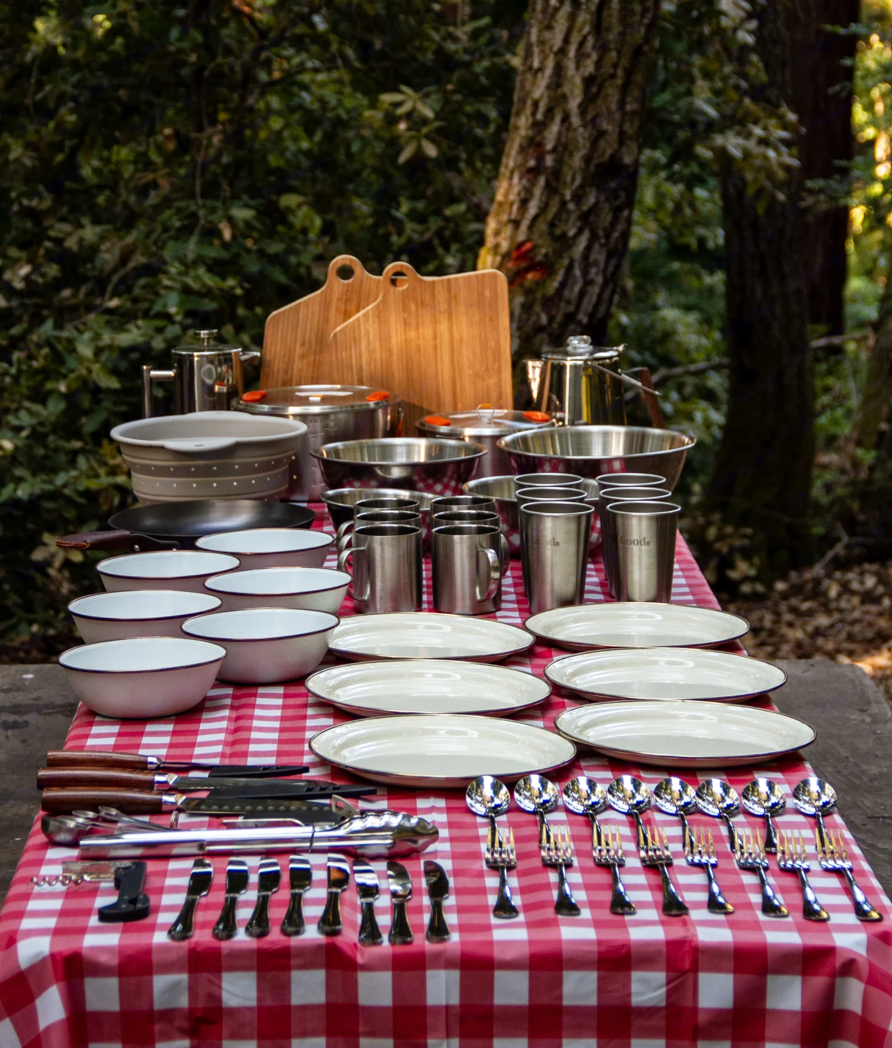 Complete outdoor cooking & dining gear for your RV rental trip: pots, plates, mugs, & utensils on a checkered picnic table.. All Good Equipment Company Teardrop Trailer 2024
