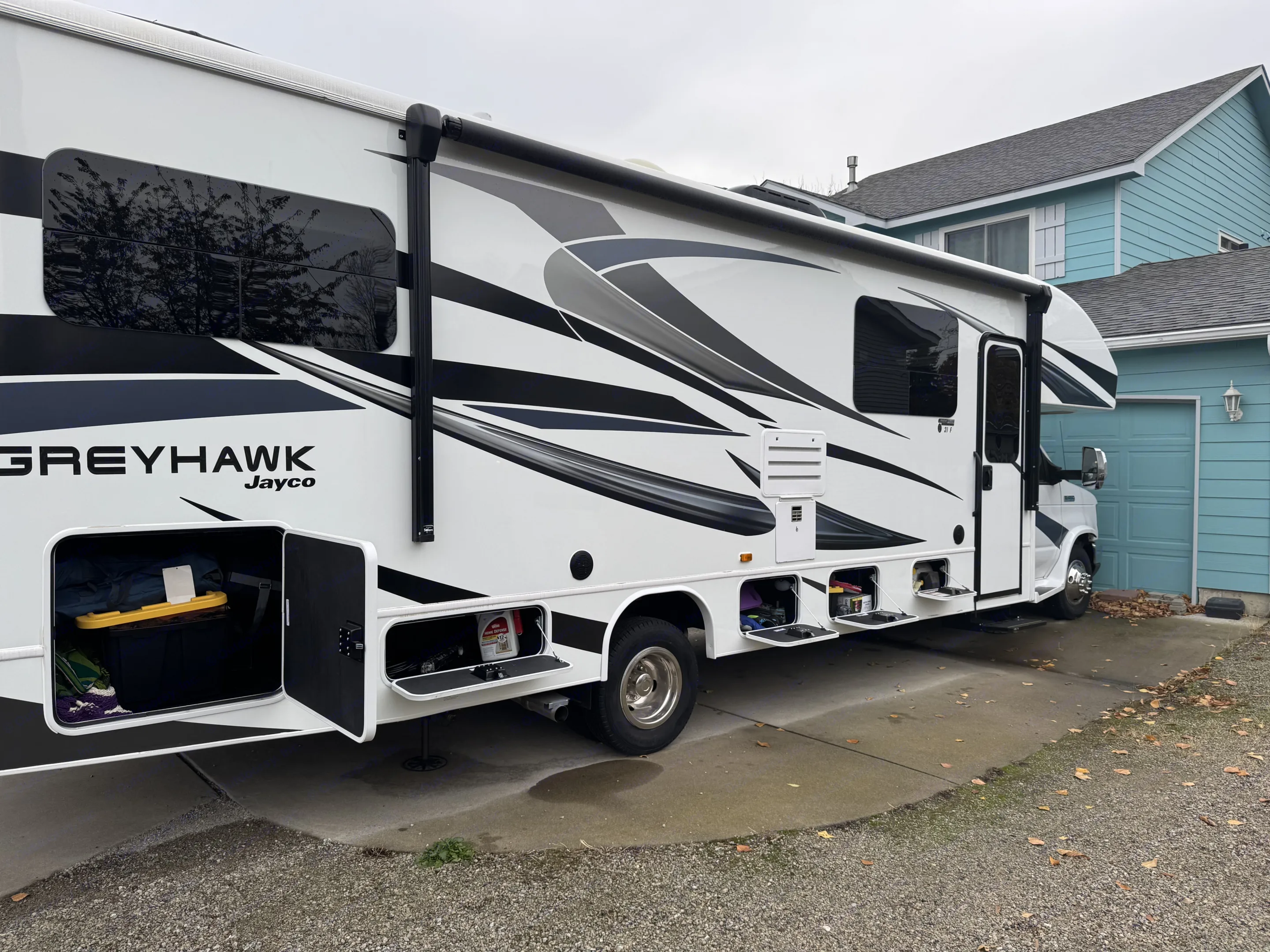 Large white Greyhawk RV rental, parked on a driveway with open exterior storage compartments, ready for adventures.. Jayco Greyhawk 2023