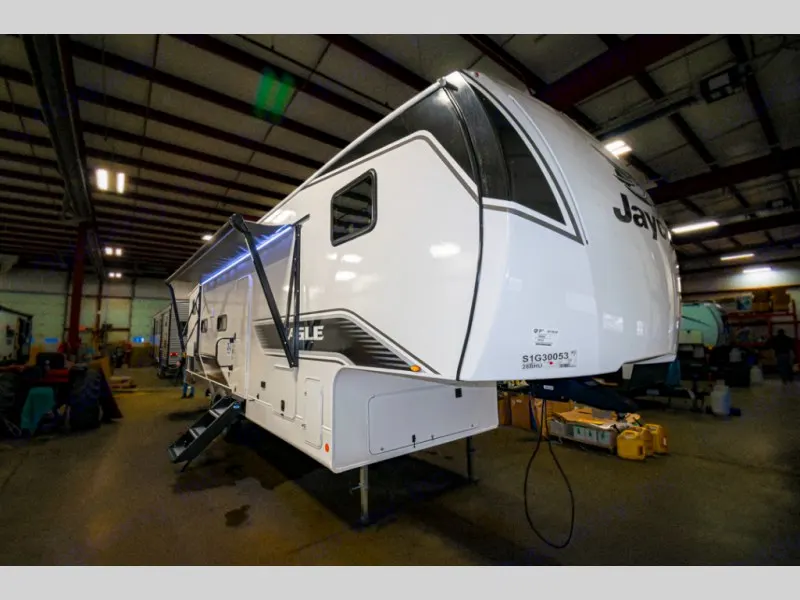 Inside a spacious factory, a white Jayco Eagle fifth-wheel RV with its awning extended, ready for an RV rental or sale.. Jayco Eagle Super Lite 2025