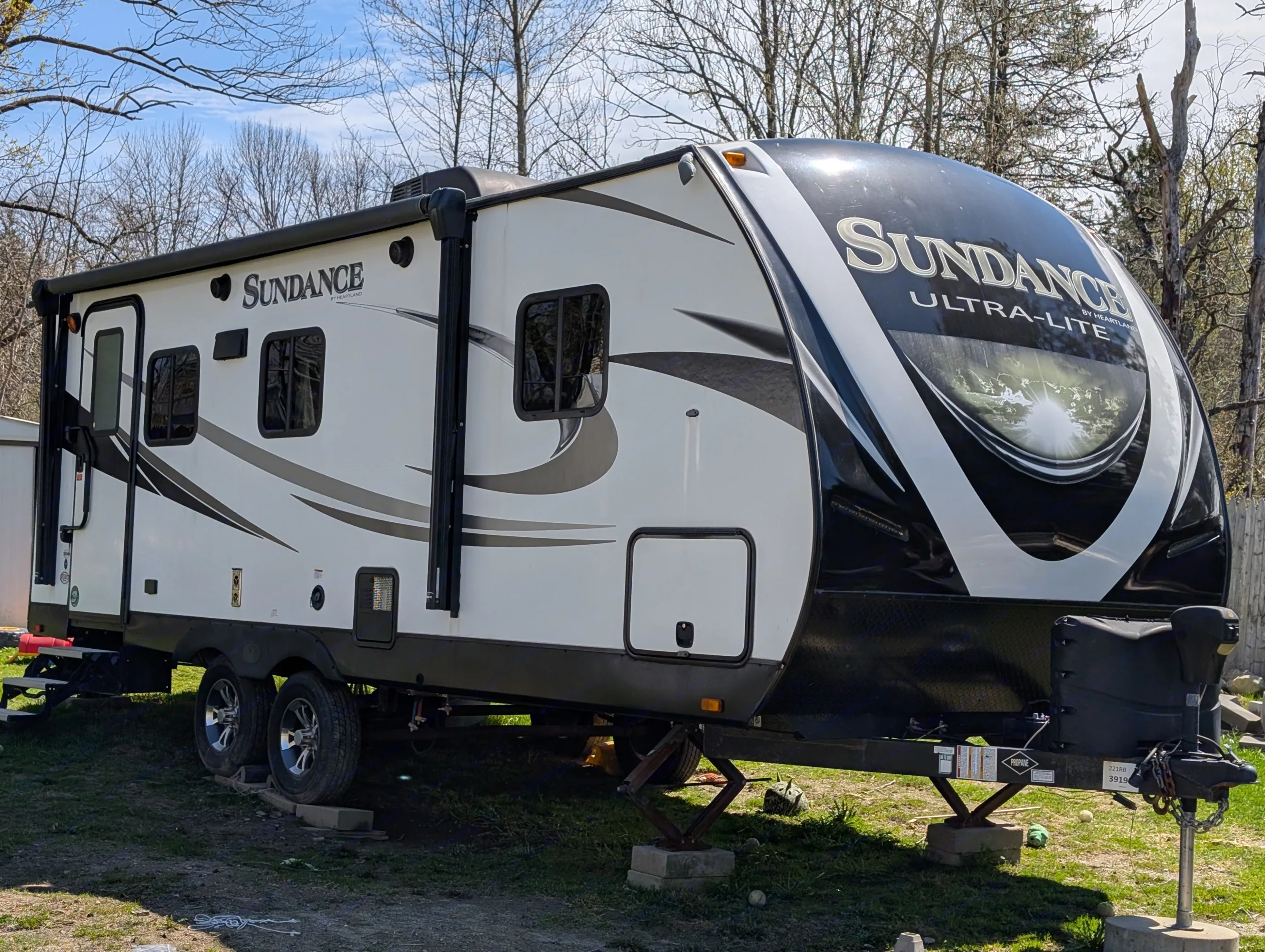 This white and black Sundance Ultra-Lite travel trailer RV is ready for an rv rental adventure, parked on grass.. Heartland RVs Sundance 2019