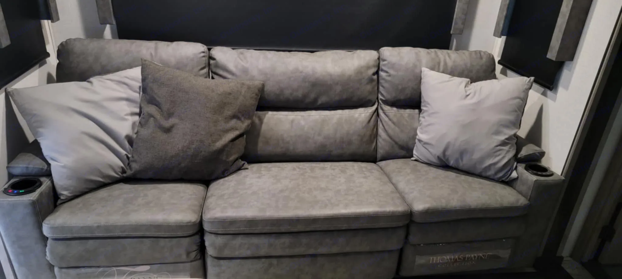 Plush gray reclining sofa with pillows in an RV rental, offering comfort and built-in cup holders.. Keystone Carbon 2021
