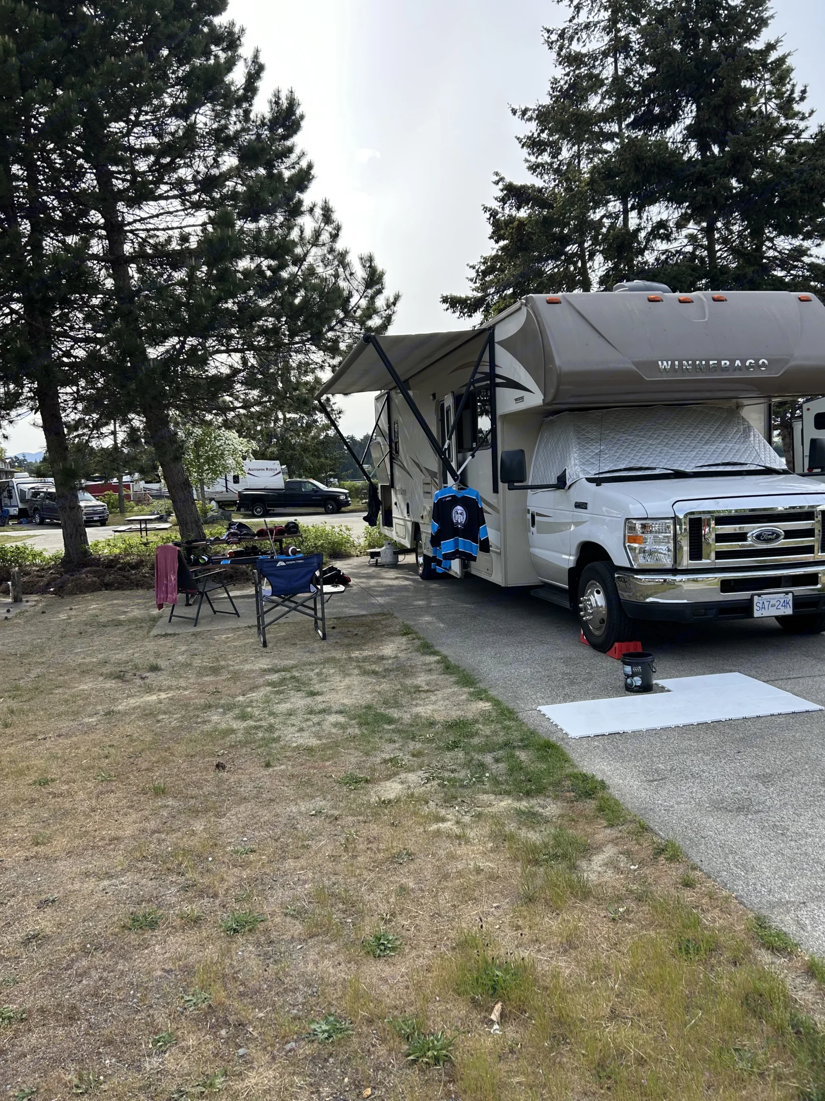 White Winnebago RV rental at a British Columbia campsite, with an extended awning and gear ready for outdoor leisure.. Winnebago Minnie Winnie 2017