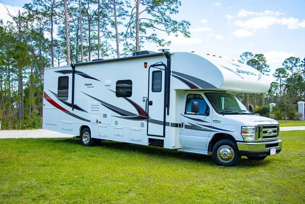A clean white Jayco Redhawk Class C rv rental parked on green grass, ready for adventure under blue skies.. Jayco Redhawk 2019