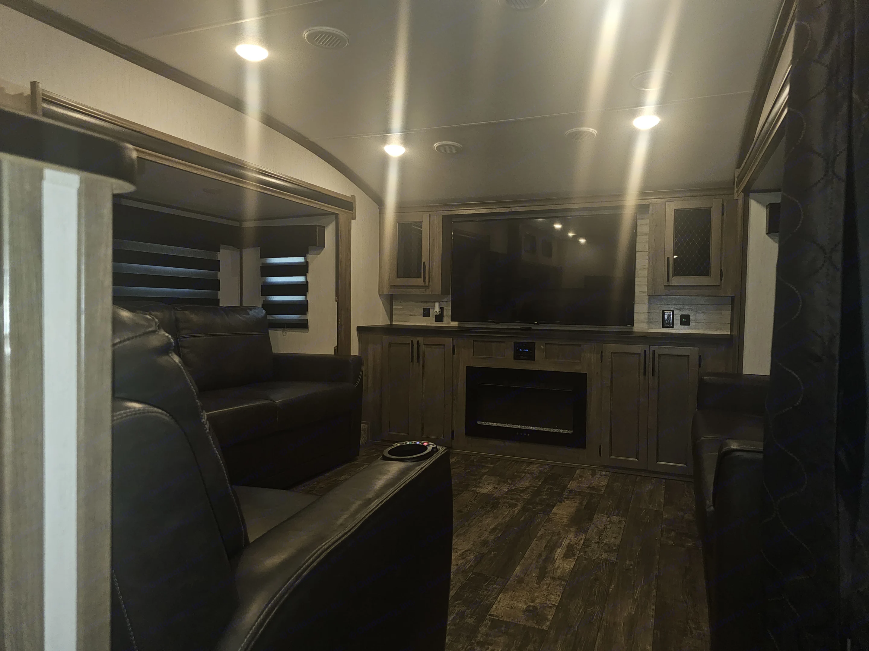 RV rental interior: Cozy living space with recliners, large TV, fireplace, and wood finishes.. Forest River Sabre 2023