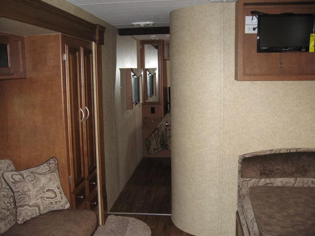Step inside this cozy RV rental! Features include a comfortable living area, wood cabinetry, a mounted TV, and a hallway to the bedroom.. Eclipse Milan 2011