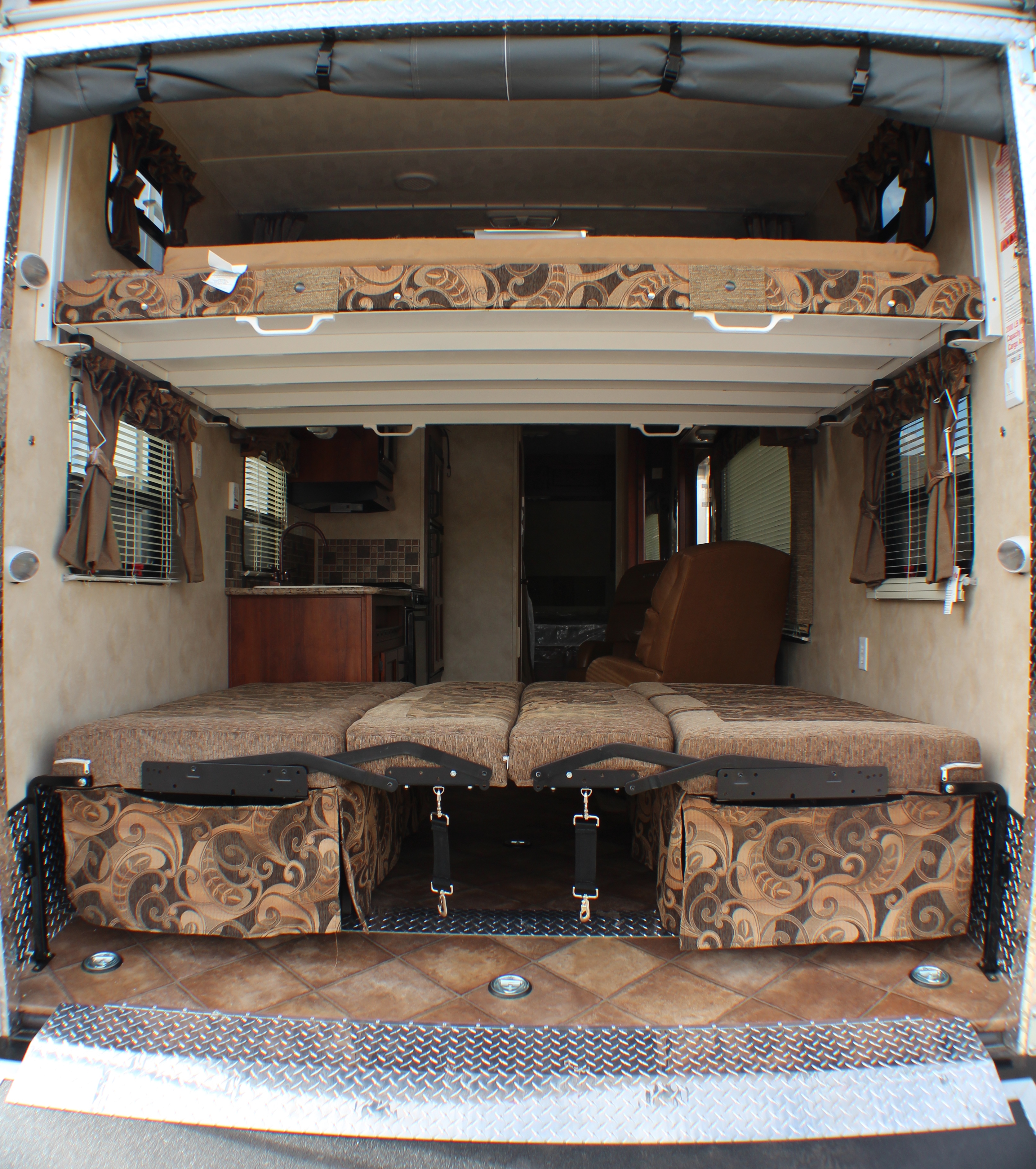 Inside this RV rental toy hauler: a versatile garage space with convertible beds, an upper bunk, and kitchen view.. Palomino Puma Unleashed 2013