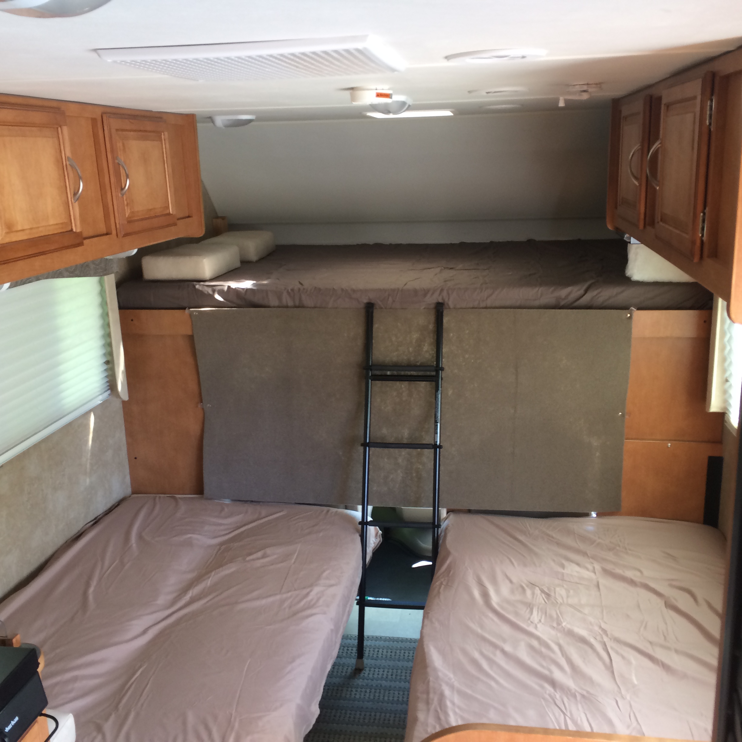 Spacious rv rental interior featuring a cabover bed, two bunk beds, a ladder, and overhead cabinets.. Winnebago Minnie Winnie 2015