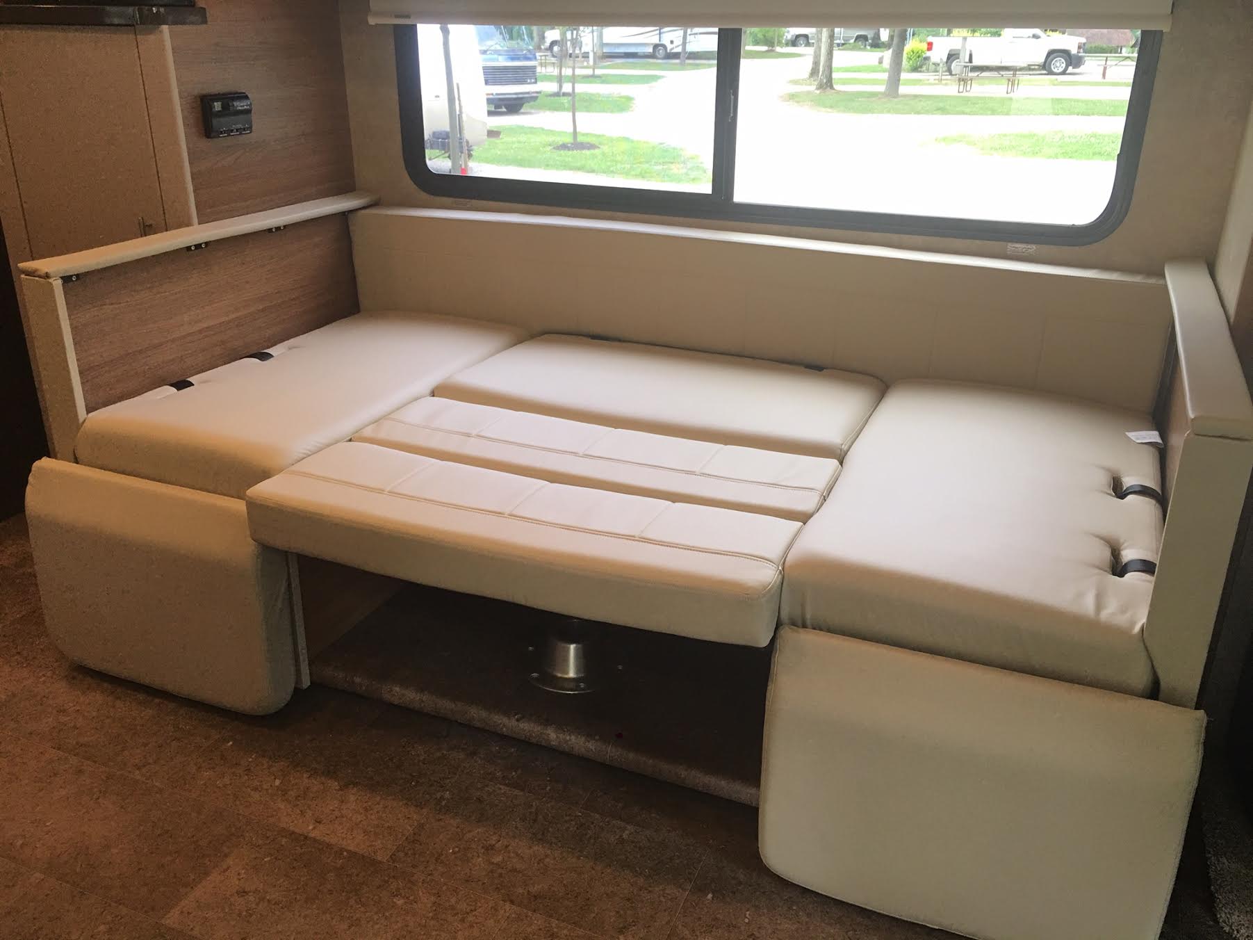 RV rental: Beige convertible dinette seating and bed area inside a motorhome, offering flexible living space.. Winnebago Navion 2017