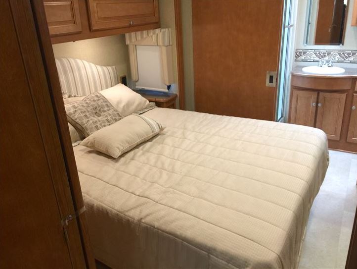 Comfortable RV rental bedroom with bed, overhead cabinets, and attached bathroom. Ideal for your mobile adventures.. Itasca Sunstar LX 35F 2016