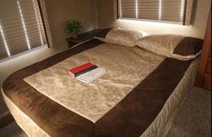 Cozy RV rental bedroom with a large bed, perfect for travel & restful sleep. Features blinds & warm decor.. Jayco GreyHawk