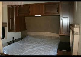 Experience an RV rental! This image shows a cozy RV bedroom with a bed, overhead cabinets, and side nightstands.. jayco jayflight 264bh 2015