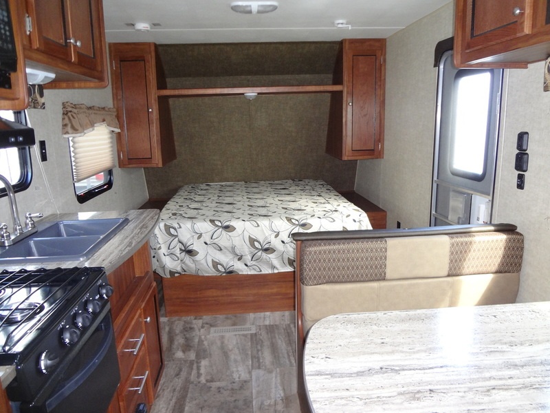 Bright and clean rv rental interior with kitchen, bed, and dining area. Ideal for road trips and camping.. Heartland Trail Runner 2017