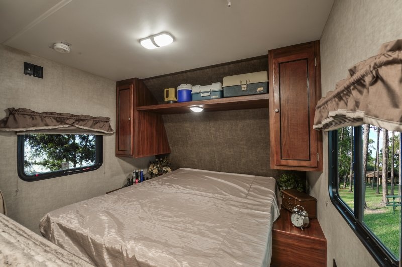 Inside an RV rental, this cozy bedroom features a bed, ample storage, and scenic window views.. Heartland Trail Runner 2015