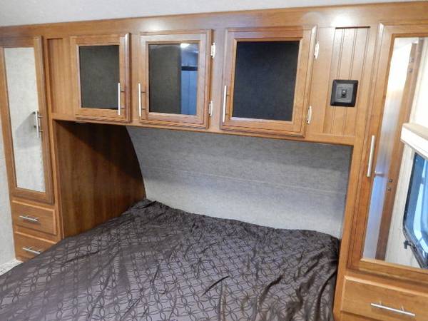 RV rental bedroom: compact with a bed, overhead cabinets, and mirrored wardrobes, offering efficient storage for travel.. Prime Time Lacrosse 2017
