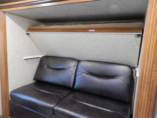 Inside an RV rental: a comfortable sofa with a space-saving pull-down bed neatly folded above it.. Prime Time Lacrosse 2017