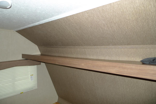 Cozy RV rental interior with an angled sleeping or storage area, featuring a wooden shelf and window.. Dutchmen Coleman 2016