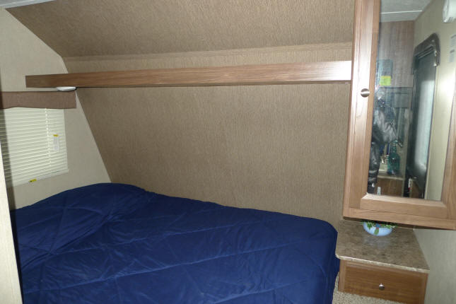 Comfortable rv rental sleeping area featuring a blue bed, window, and mirrored cabinet for storage.. Dutchmen Coleman 2016